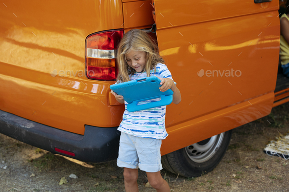 Little boys using the tablet on a wonderful day camping in a van. Van life concept.