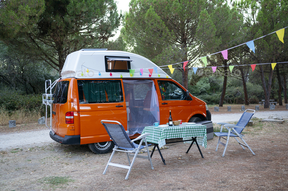 Camper van in the field with chairs and table for recreation. van life concept .