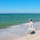 a girl walks along the shore of the blue sea on the sandy shore. summer mood - PhotoDune Item for Sale