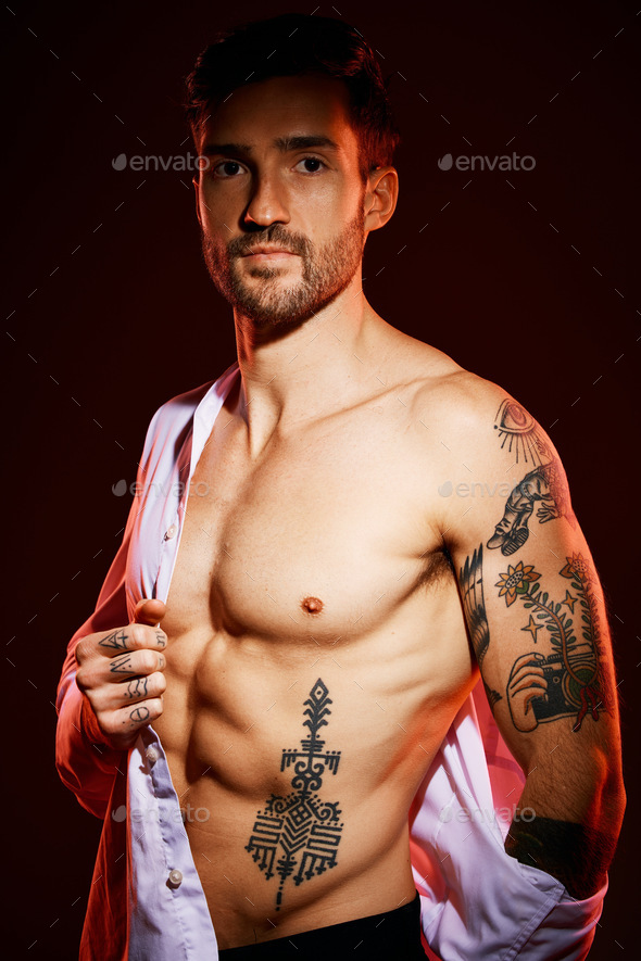 Fashion, sexy and portrait of a man in a studio with muscles, body and tattoos for body care or fit Stock Photo by YuriArcursPeopleimages