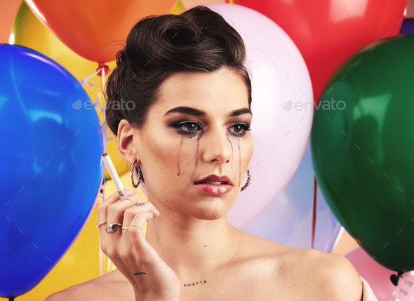 Party balloon and makeup woman crying with sad, depressed and disappointed tears on face. Thinking,