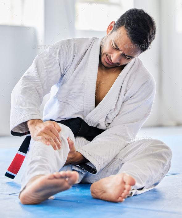 Injury, karate and man with knee pain after an accident in martial arts training in a wellness stu