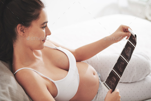 Love at first sight. Shot of a pregnant woman looking at a sonogram picture at home.