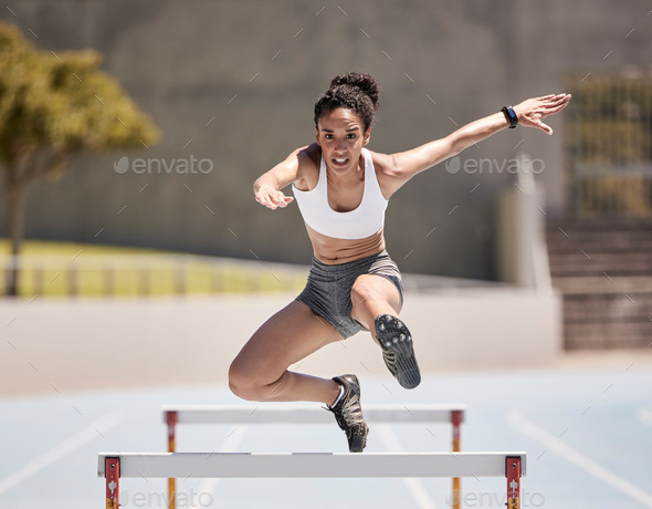 Jump, athlete and hurdle black woman in sports race, competition or training at stadium with energy