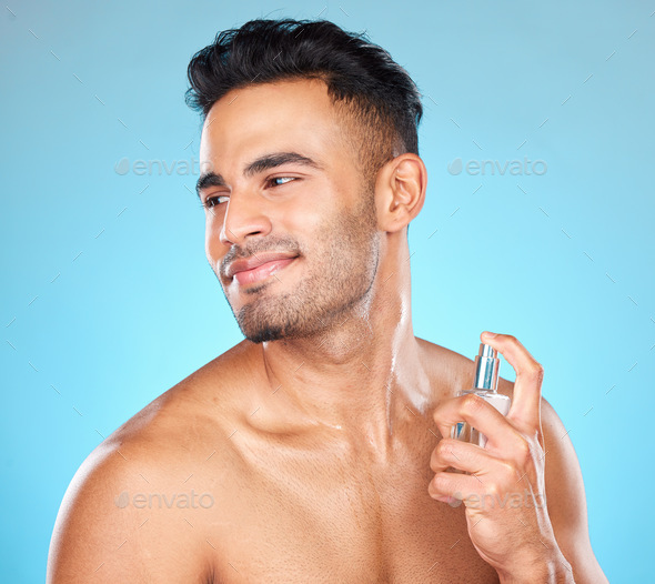 Man, smile and perfume for aroma, fragrance and natural beauty against blue studio background. Youn