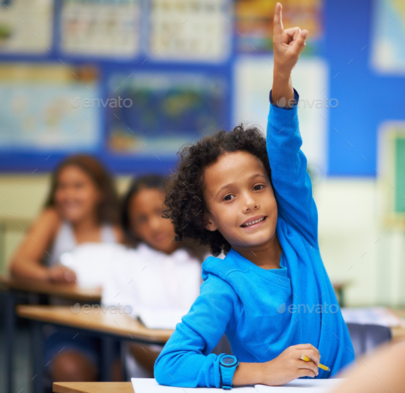 Pick me I know the answer. A little boy raising her hand in class.