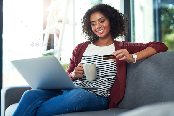 Me time is treat time. Shot of a young woman using a laptop and credit card on the sofa at home.