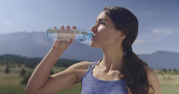 Slow Motion Shot of Sporty Trail Running Woman While Drinking Water and Resting From Intense Jogging alt