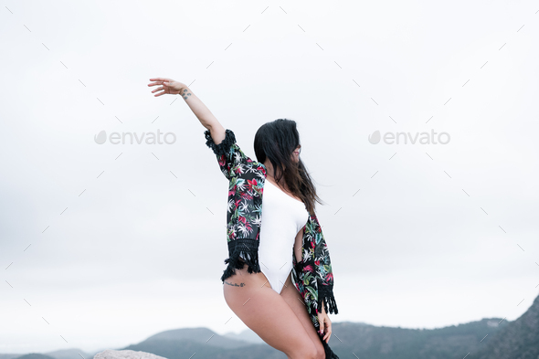 Caucasian mature woman dancing on the mountain in contact with nature right arm outstretched doing
