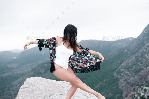 Caucasian mature woman in white swimsuit and fringed sarong doing ballet calm and alone on a big - Stock Photo - Images