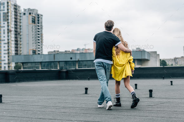 back view of woman in yellow jacket and man in jeans and t-shirt ...