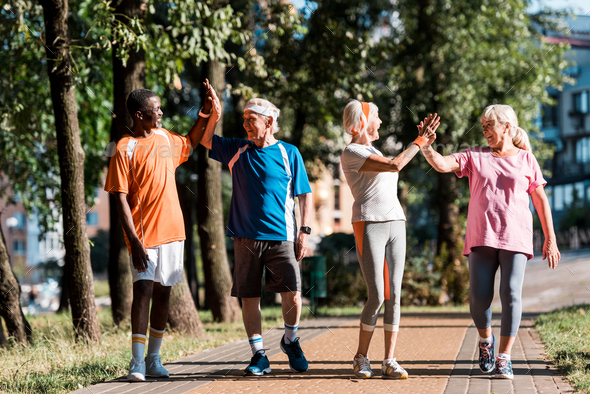 happy multicultural group of retired men and women giving high five in ...