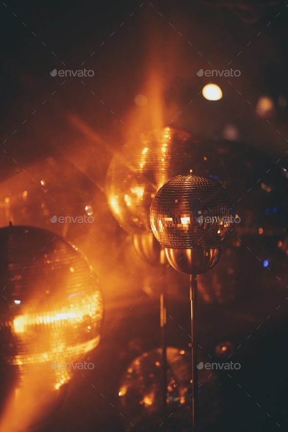 Closeup of mini disco balls under red and orange lights with a blurry  background Stock Photo by wirestock
