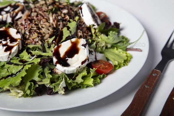 salad with sunflower seeds lettuce tomatoes and burrata cheese glazed with balsamic vinegar