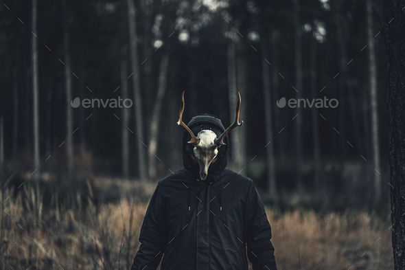 Person wearing a creepy Taxidermy mask in an autumn forest