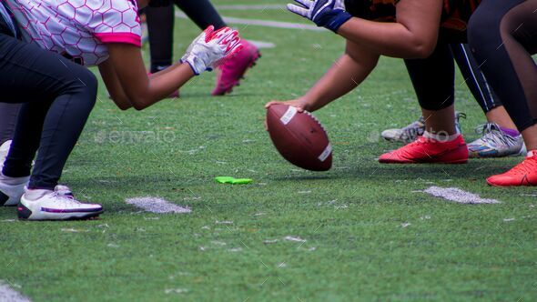 Closeup shot of American football players kicking off  a match on a green field - Stock Photo - Images
