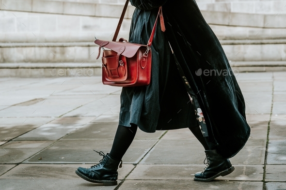 Person in a black coat carrying satchel bag while walking on the street
