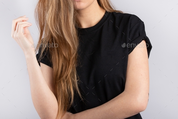 Young female wearing a black short sleeve t-shirt with a white wall in the background