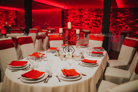 Closeup of prepared tables under red led lights for a wedding celebration in a restaurant