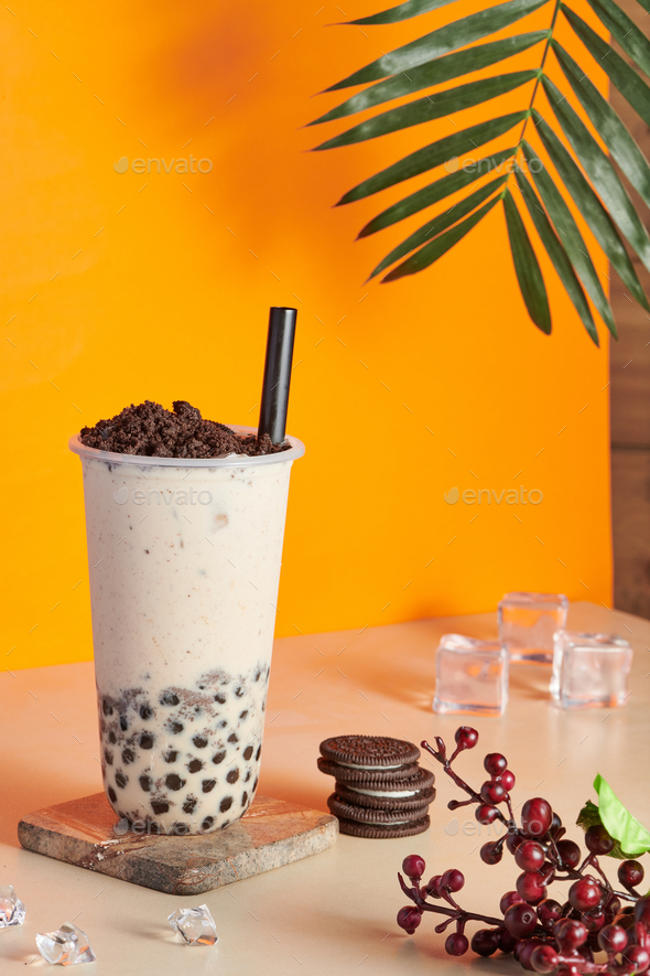 Plastic cup filled with fresh bubble milk tea with crushed cookie chocolate on the top