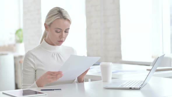 Young Businesswoman Reading Documents in Modern Office alt