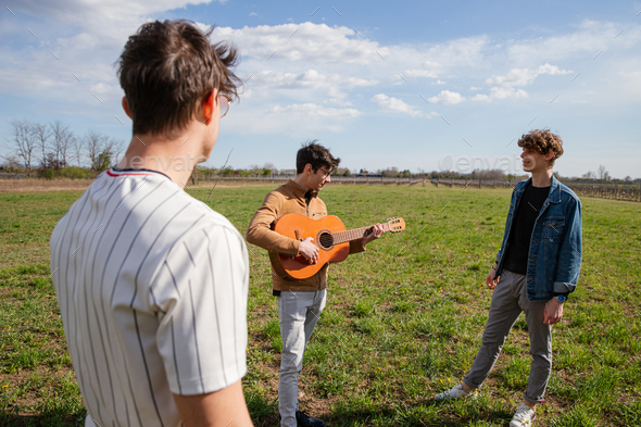 Friends meet in a meadow in the open air with a guitar and sing songs, passion for music concept
