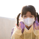 Portrait Asian cute girl wearing white mask. Child smiled sweetly, holding up two fingers in V shape - PhotoDune Item for Sale