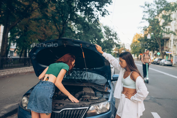 Two women with broken car on the road. Open hood - Stock Photo - Images