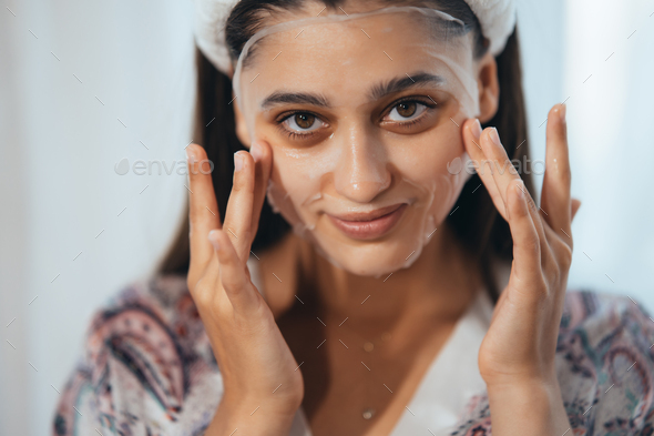 Beautiful model applying cosmetic cream treatment on her face - Stock Photo - Images