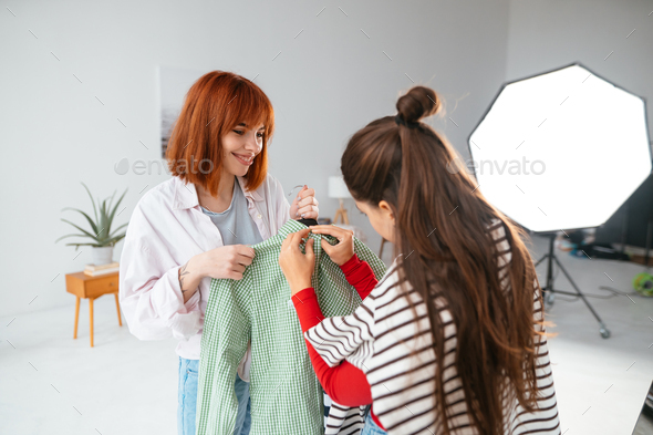 Happy beautiful young woman choosing clothes with girlfriend. - Stock Photo - Images
