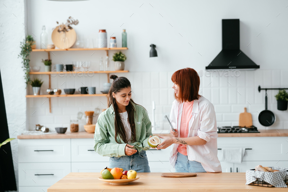 Two girlfriends cut fruit in the kitchen - Stock Photo - Images