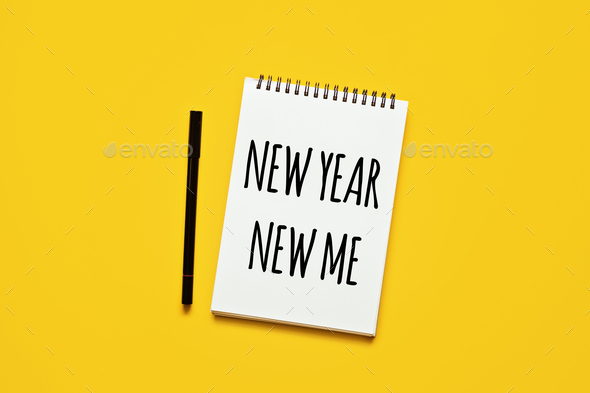 New year new me text in open notepad on yellow background. Setting goals and new years resolution