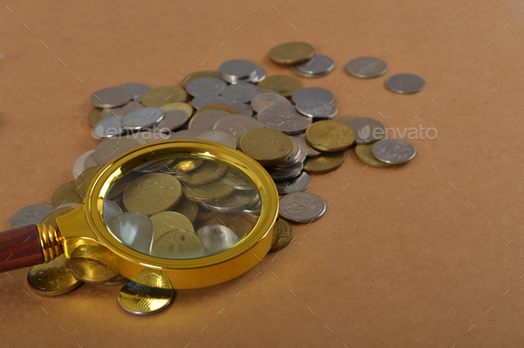 Pile of coins and magnifying glass. Finance, economy, stock market