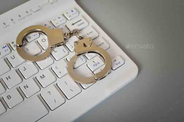 Laptop keyboard and handcuffs. Online scam, hacking. fraud, arrest and criminal concept.