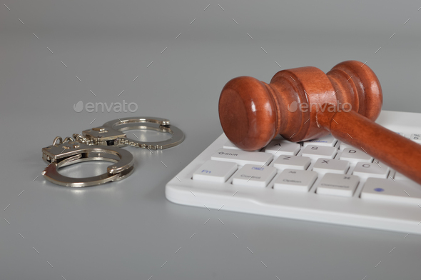Judge gavel, laptop keyboard and handcuffs. Online scam, fraud, arrest and criminal concept.