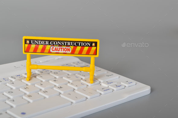 Laptop keyboard and under construction sign. Website maintenance, programming, repair, coding.