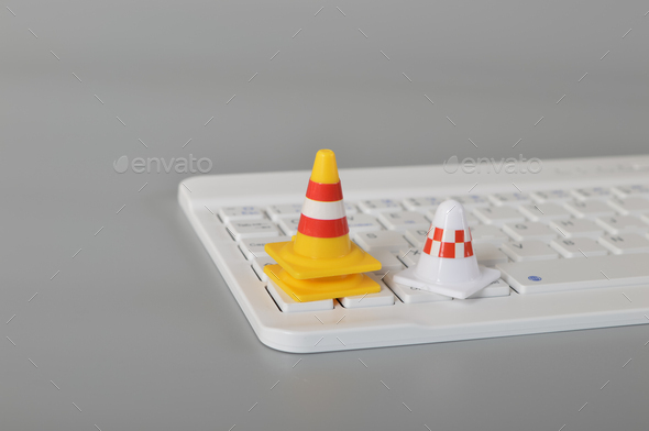 Traffic cones and laptop keyboard.Computer system under construction, repair and maintenance concept