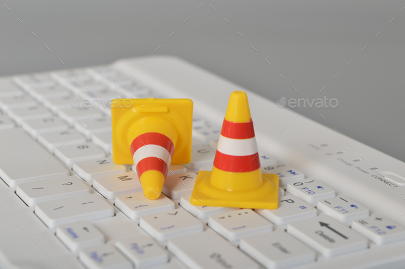 Traffic cones and laptop keyboard.Computer system under construction, repair and maintenance concept