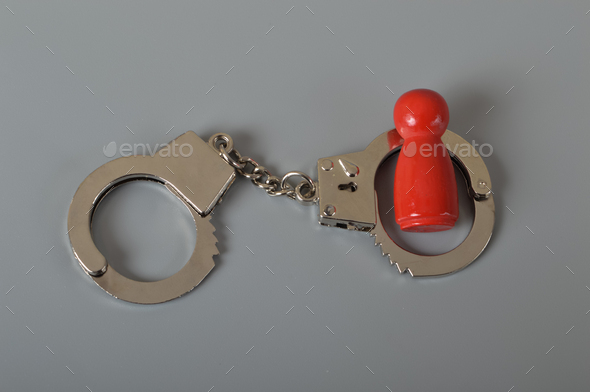 Red wooden people of figure with handcuff locked. Handcuffed convict, law offender and justice