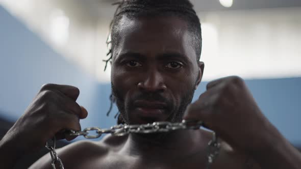 Headshot Portrait of Confident Serious Strong Man Stretching Metal Chain with Hands Looking at alt