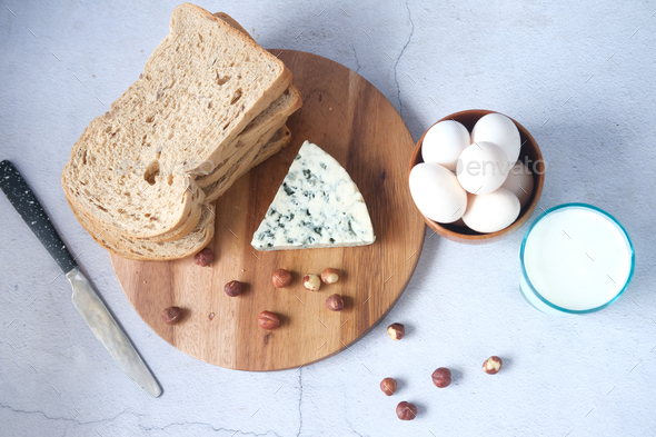 blue cheese, milk , brown bread , egg and almond nut on table.