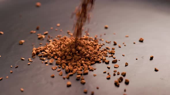 Instant Coffee Granules Drop in Slow Motion Onto a Black Surface and Form a Small Pile alt