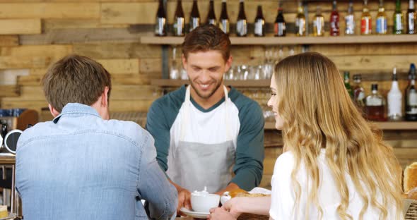 Waiter serving cup of coffee to customers at counter 4k alt