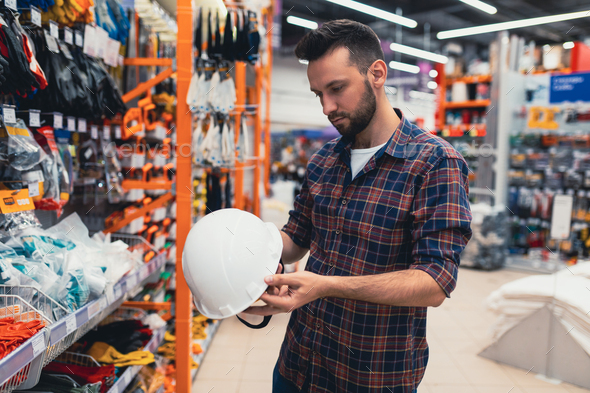 a builder in a building materials store chooses a protective helmet, the concept of safety during