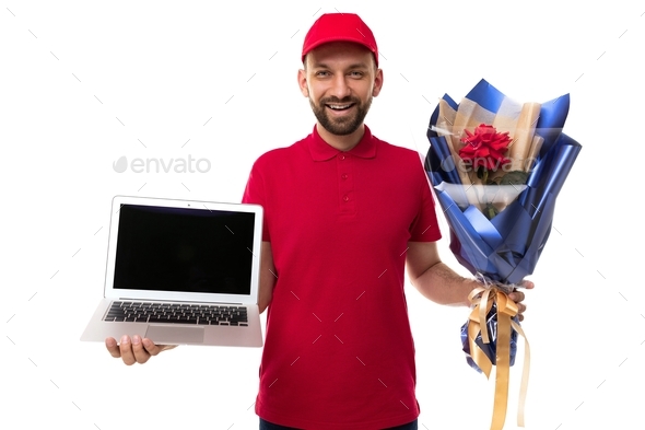 courier with flowers in hand and red uniform demonstrates new proposal on laptop screen, photo on