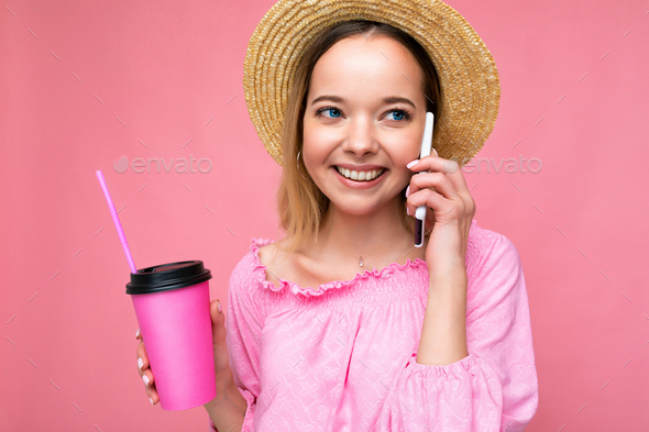 Portrait of beautiful positive emotional young blonde woman wearing pink crop blouse and straw hat