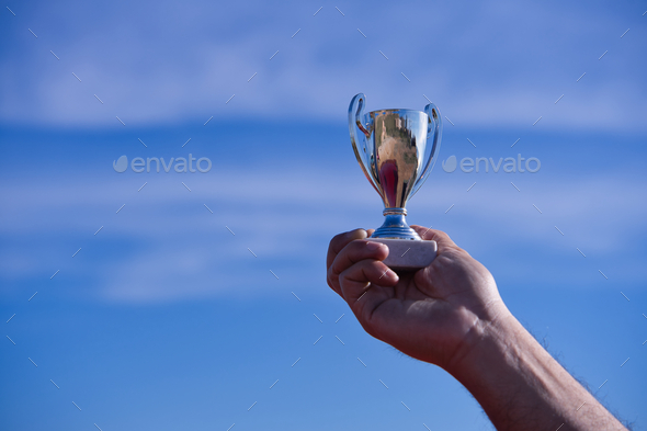 Male hand holds a silver cup.