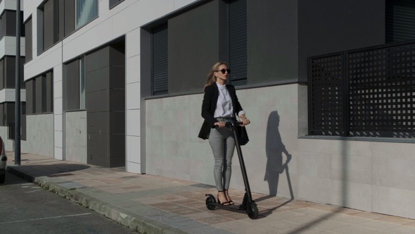 Woman traveling on electric scooter on the sidewalk alt