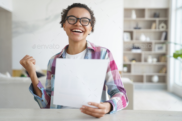 Excited mixed race student girl holds university admission letter celebrates achievement, success