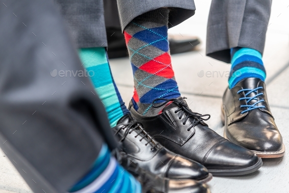 Closeup shot of men wearing patterned colorful socks with suits and classy shoes